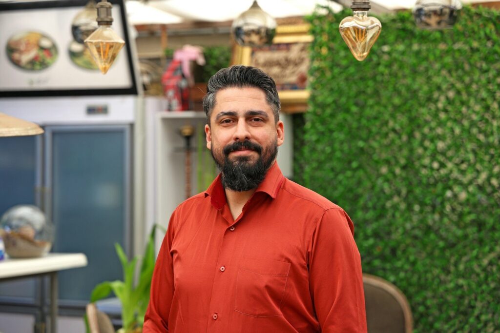 Man with beard in a red shirt smiling indoors